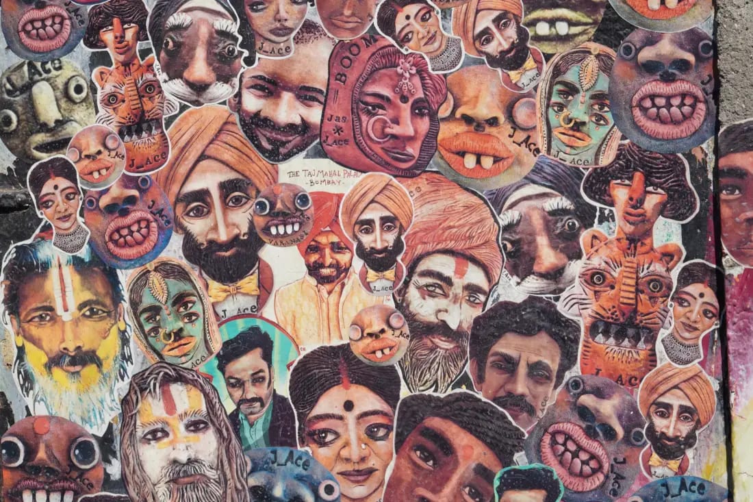 A painted wall of many faces crowded together, portraits in bright colour